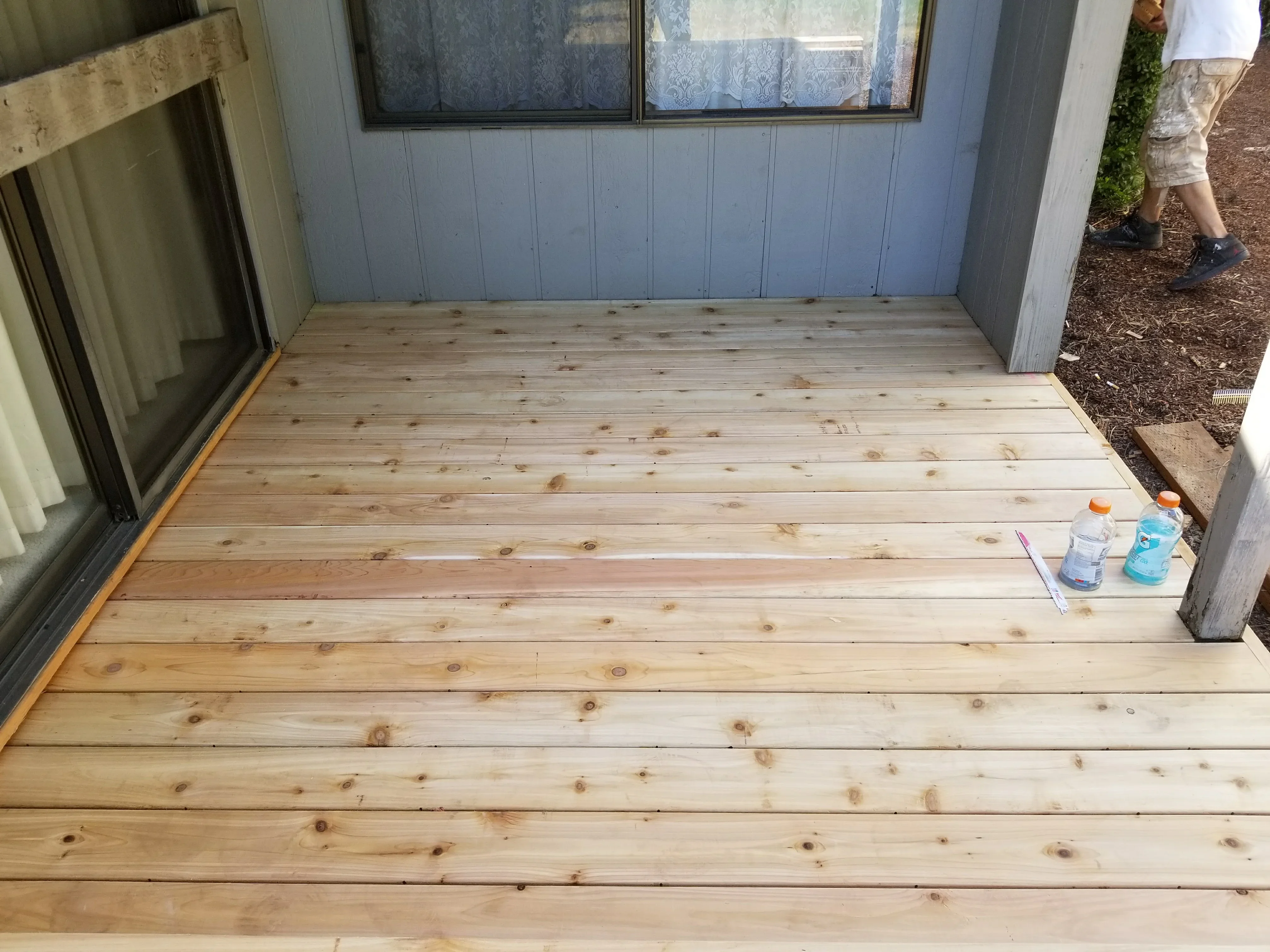 Newly installed pressure-treated wood deck with 2x6 boards and house flashing detail