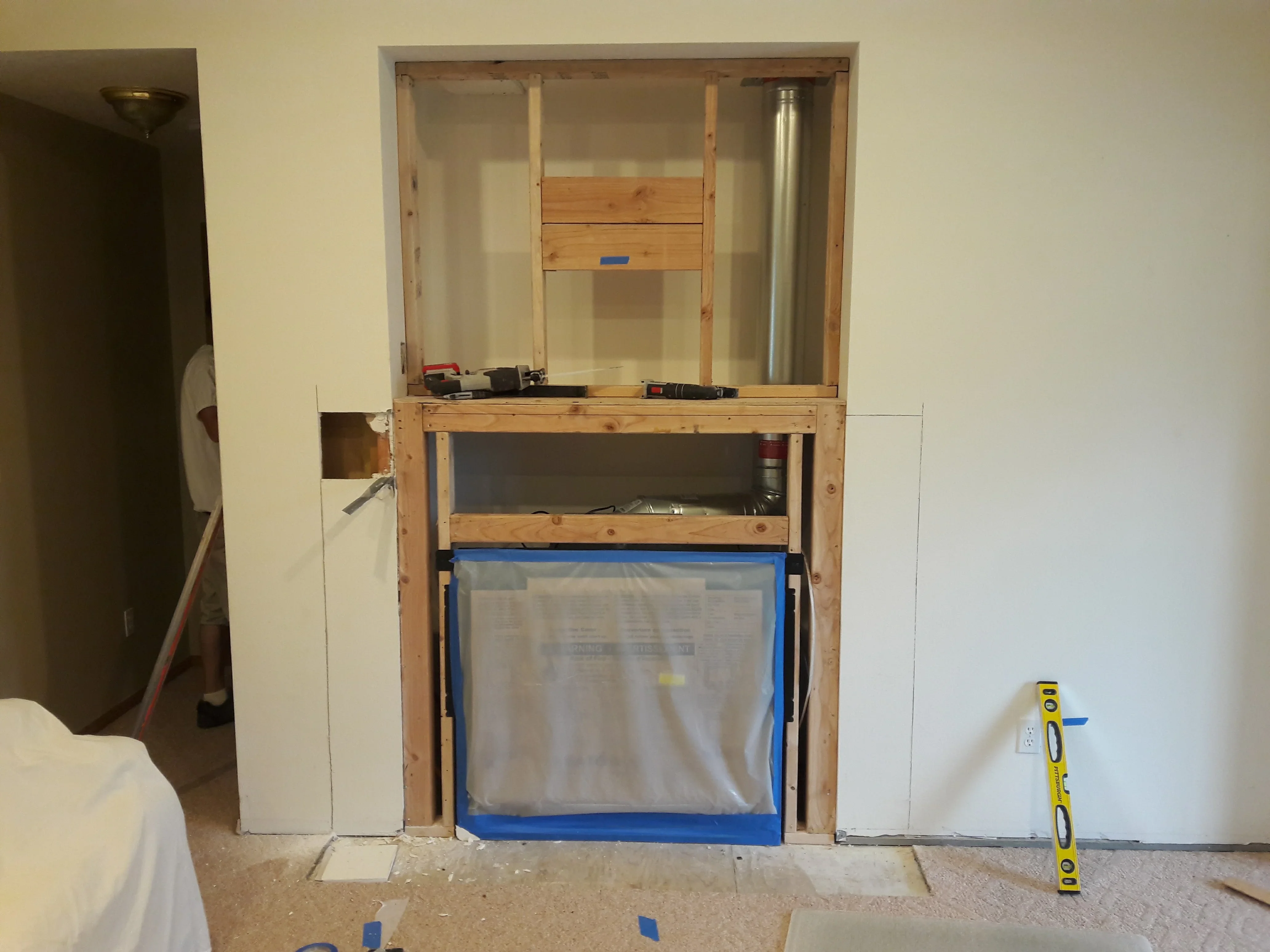 Wooden framing soffit with plastic protection and blue tape masking in kitchen renovation