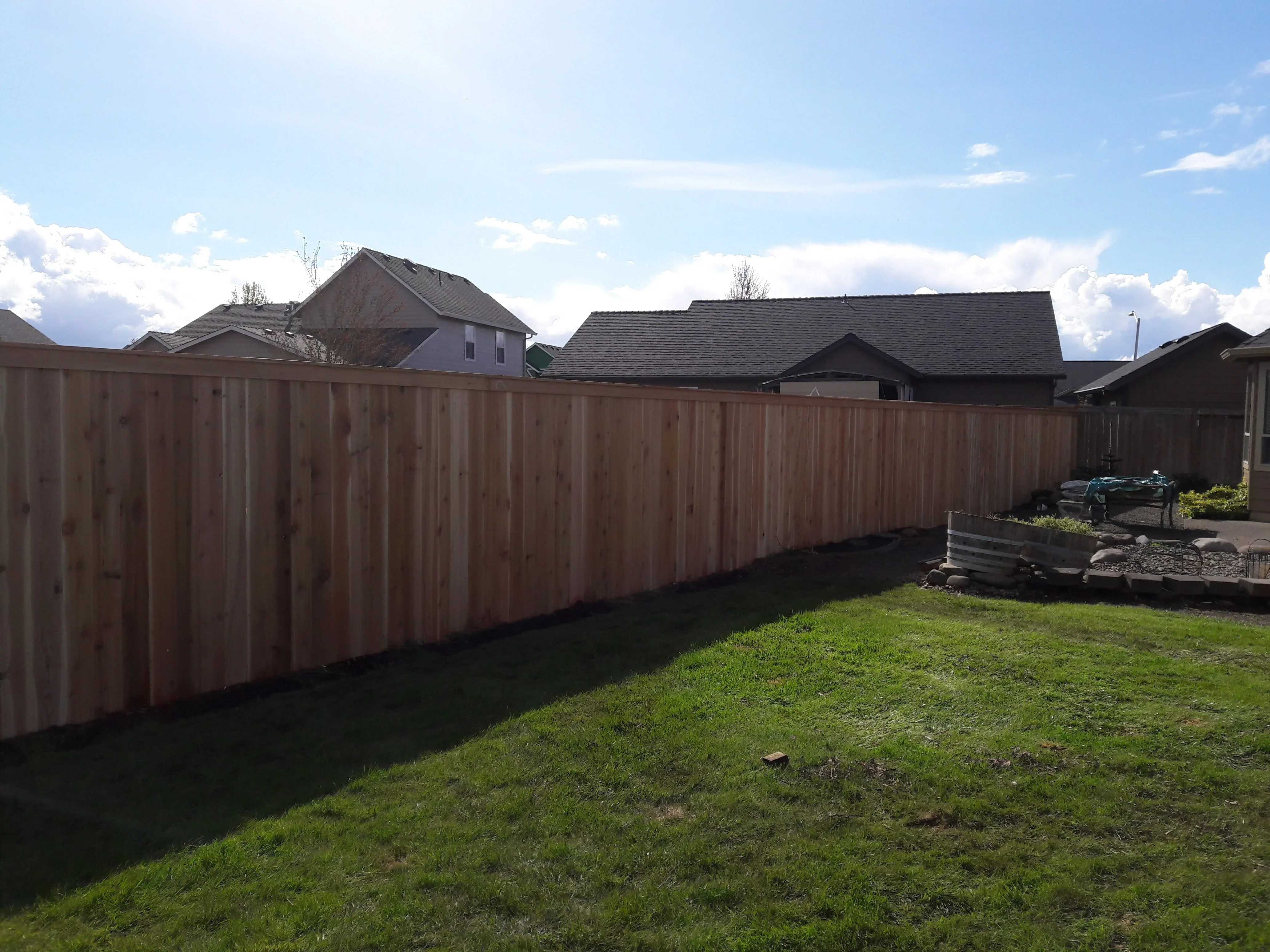 Newly installed wood privacy fence with vertical planks along residential backyard