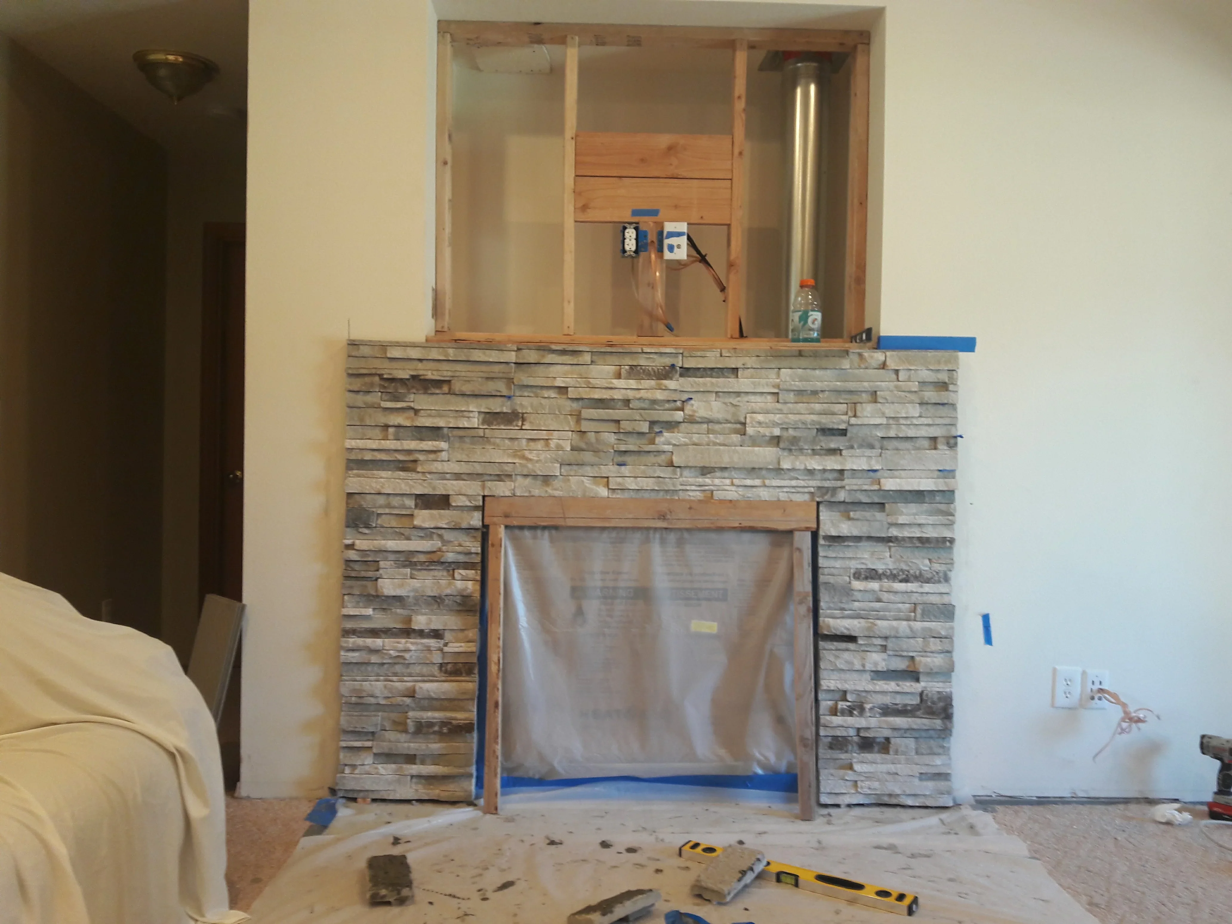 Stacked stone veneer fireplace with varied earth-tone stones and wooden frame opening