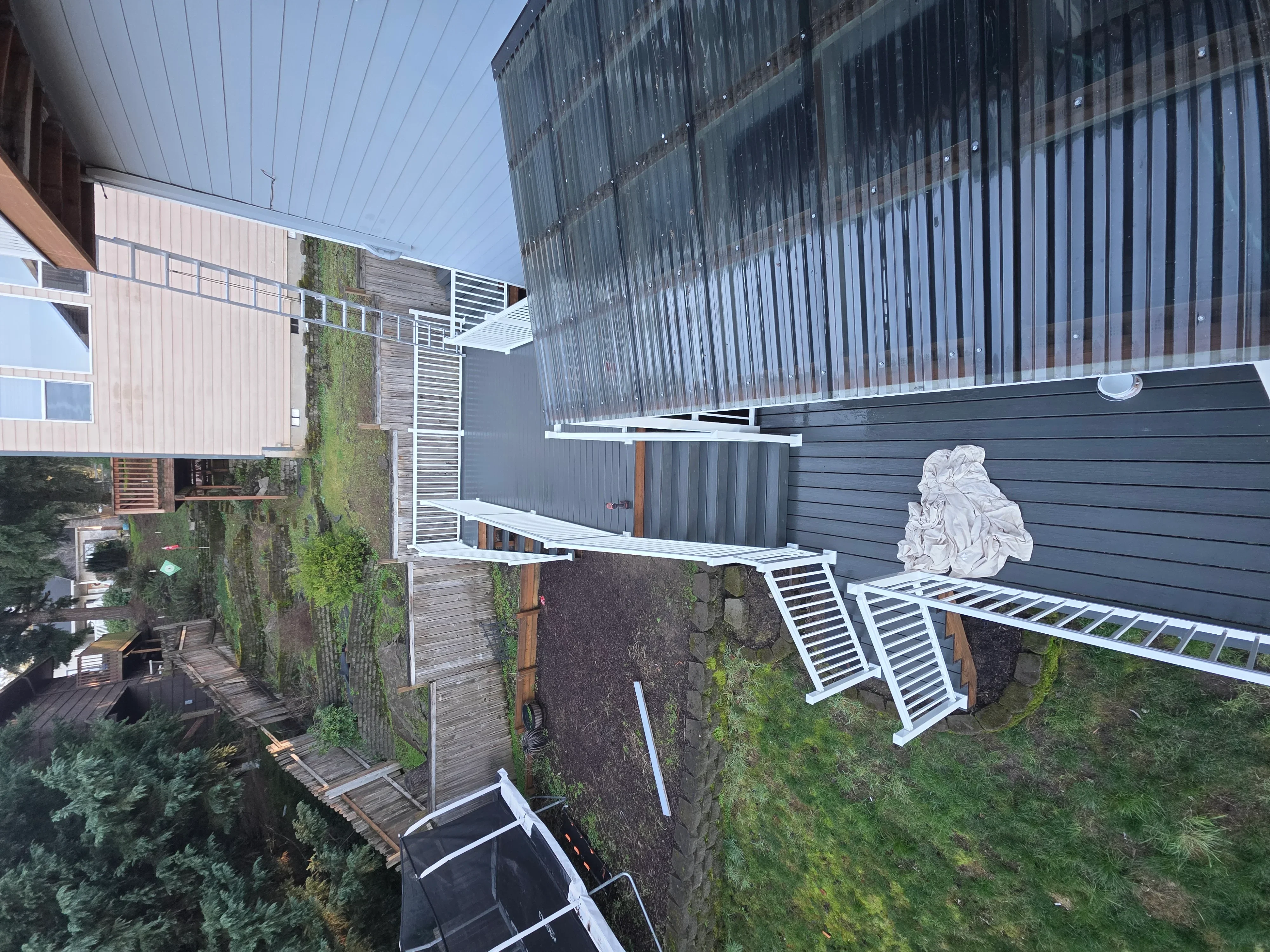 Charcoal metal siding with white trim, composite deck, and aluminum railings on residential exterior