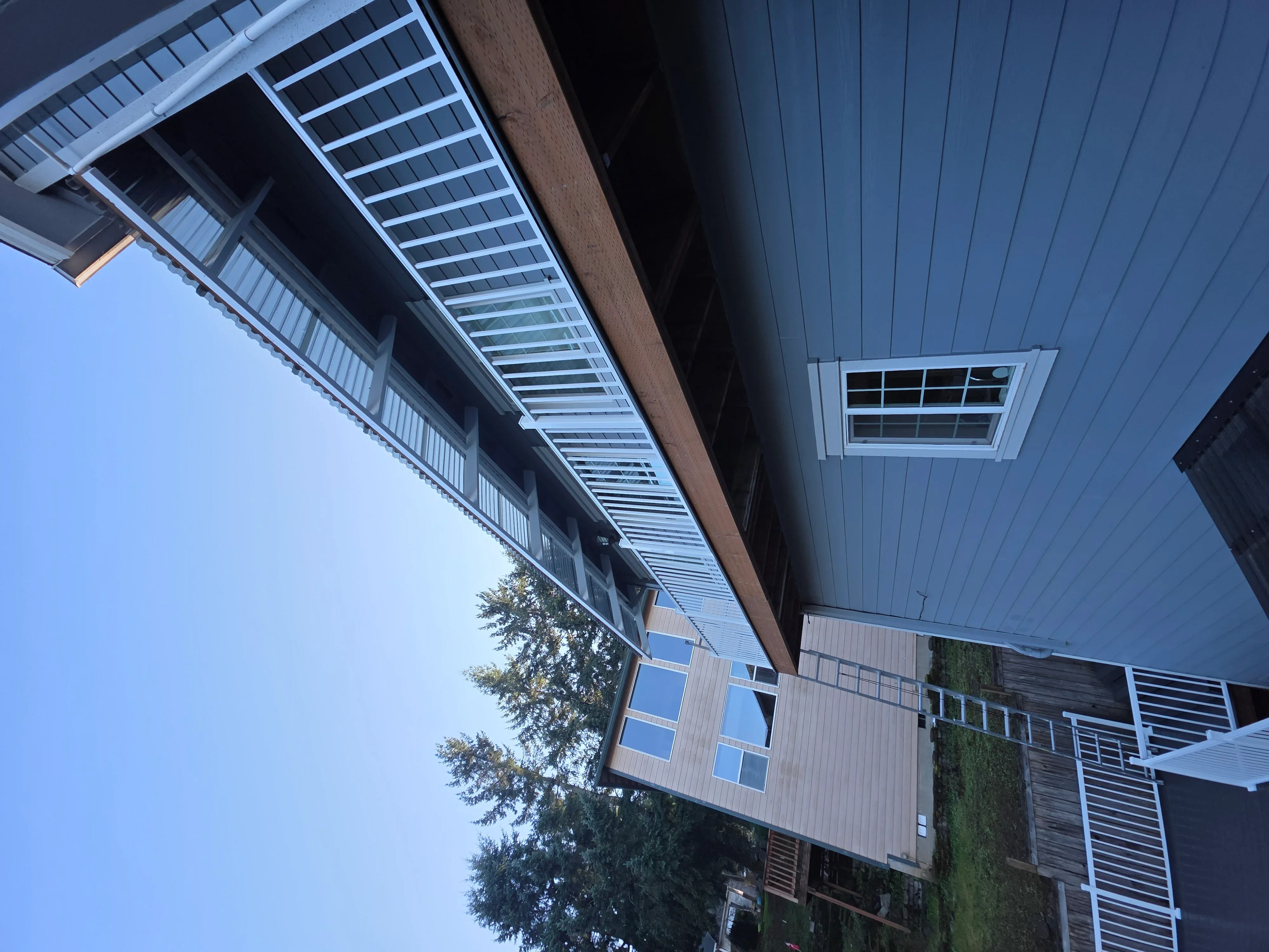 Metal standing seam roof with vertical siding, skylight, and soffit installation on residential building