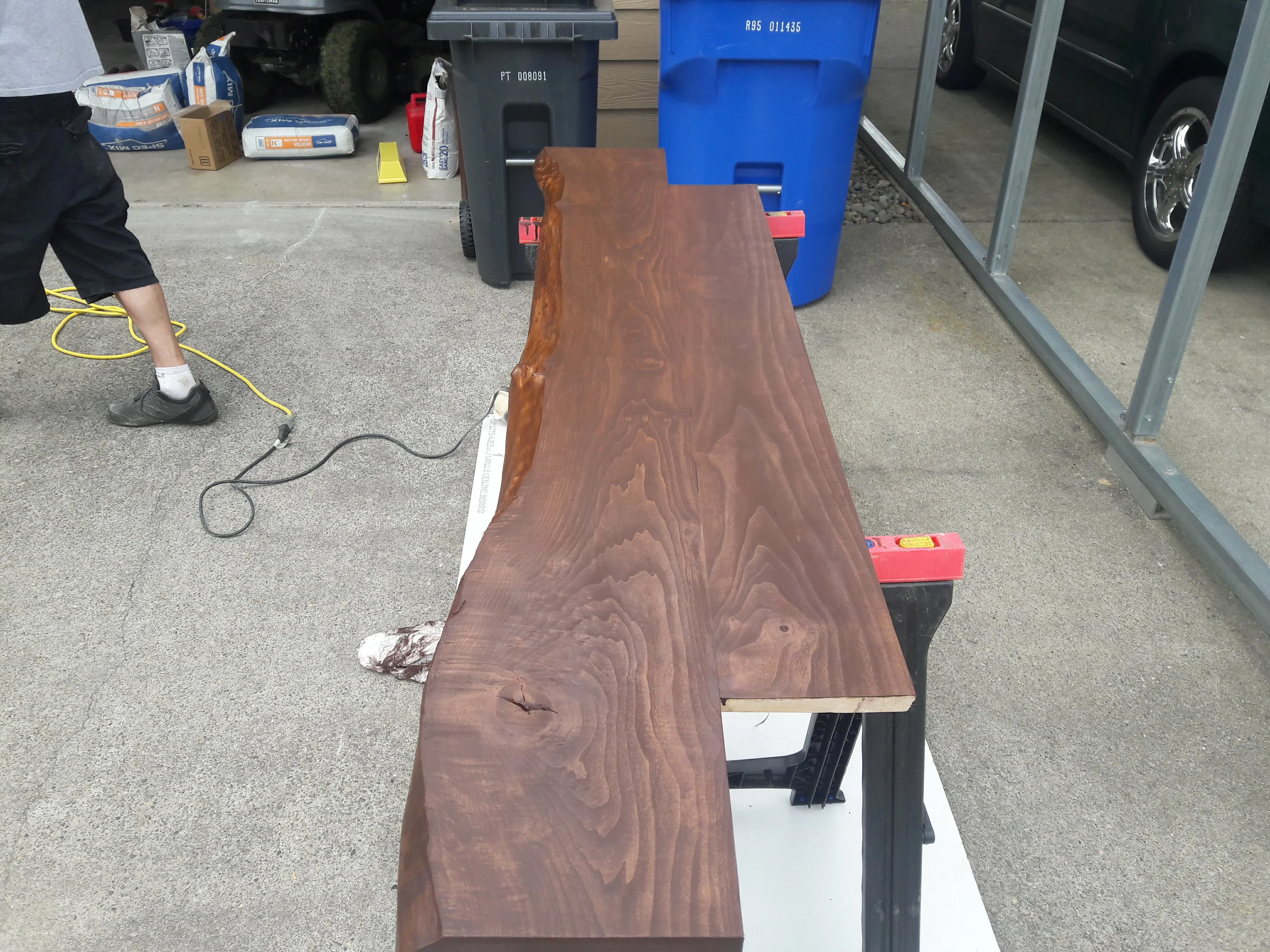 Live edge wood slab with rich brown finish and natural grain patterns during finishing process