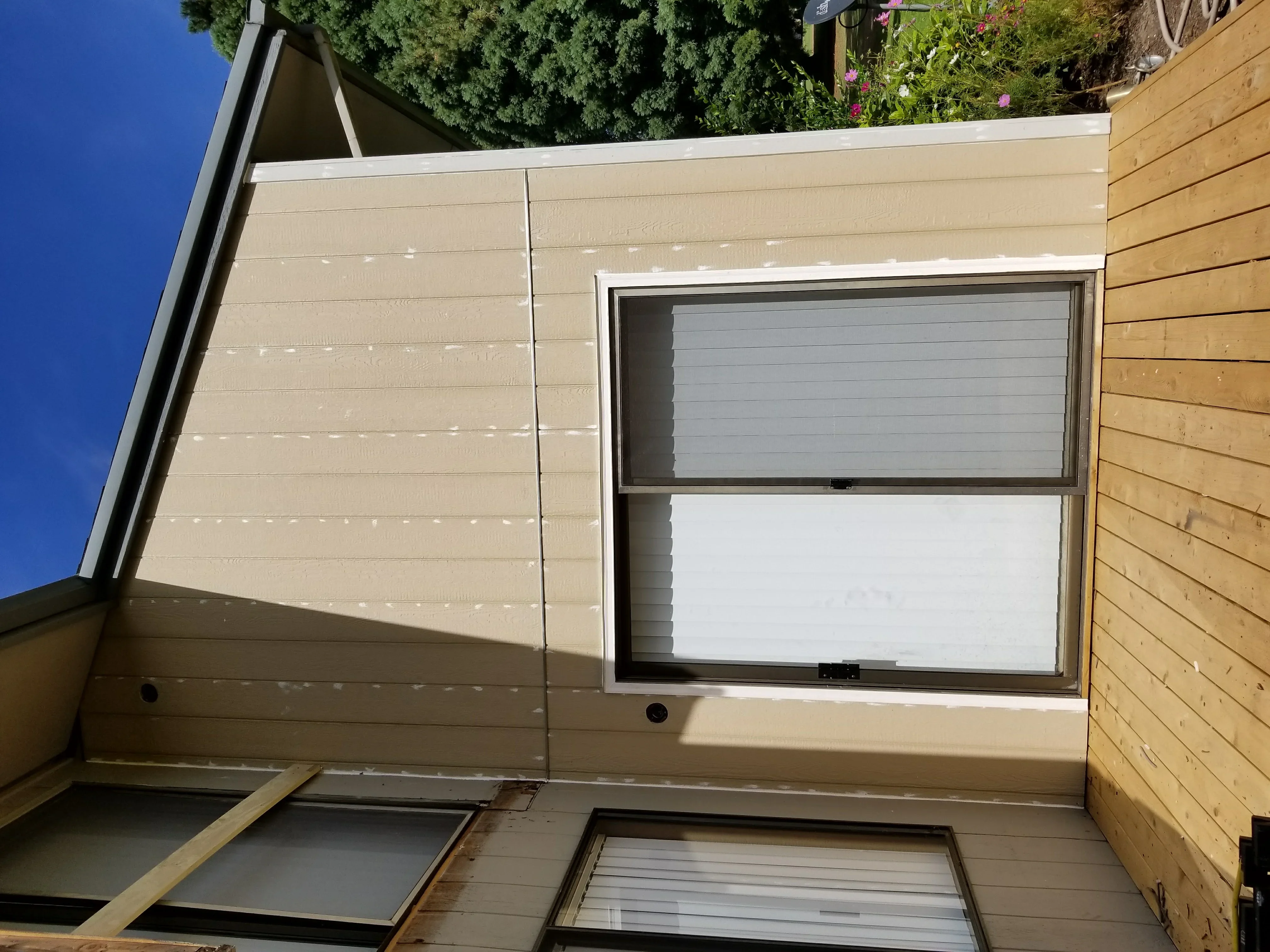 Tan fiber cement siding garage with fixed window, horizontal wood siding accent wall