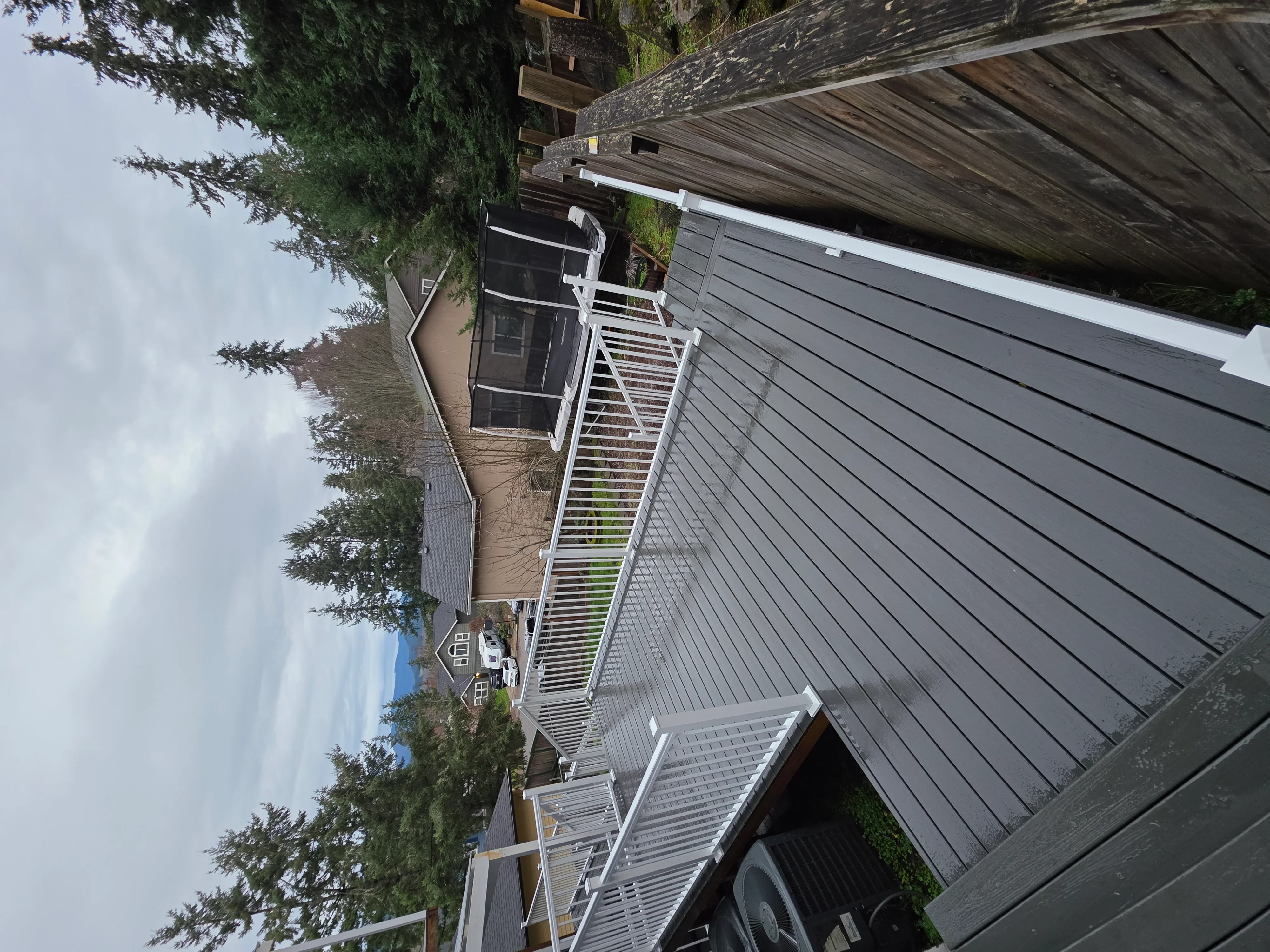 Gray composite deck with white aluminum railings and integrated drainage system