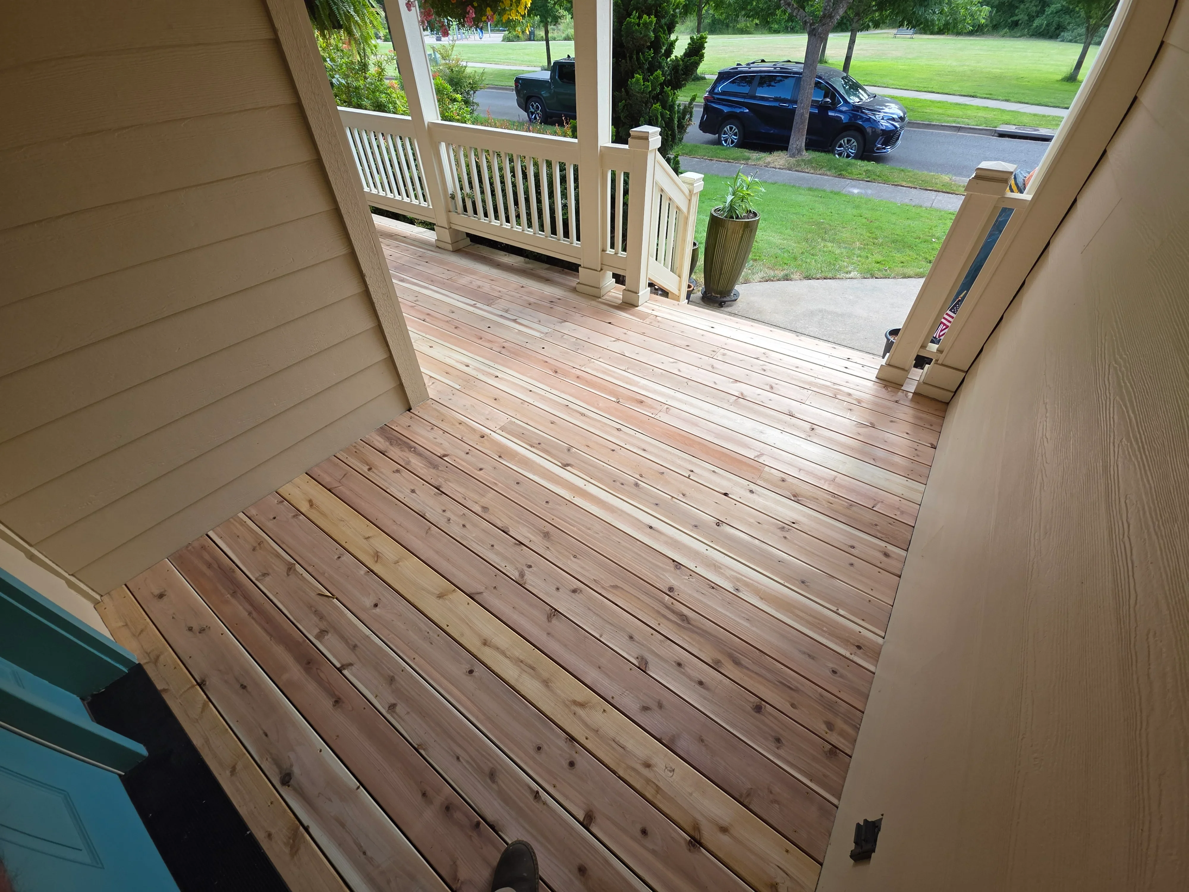 Newly constructed wood deck with diagonal boards, white vinyl railing, and glass door entry