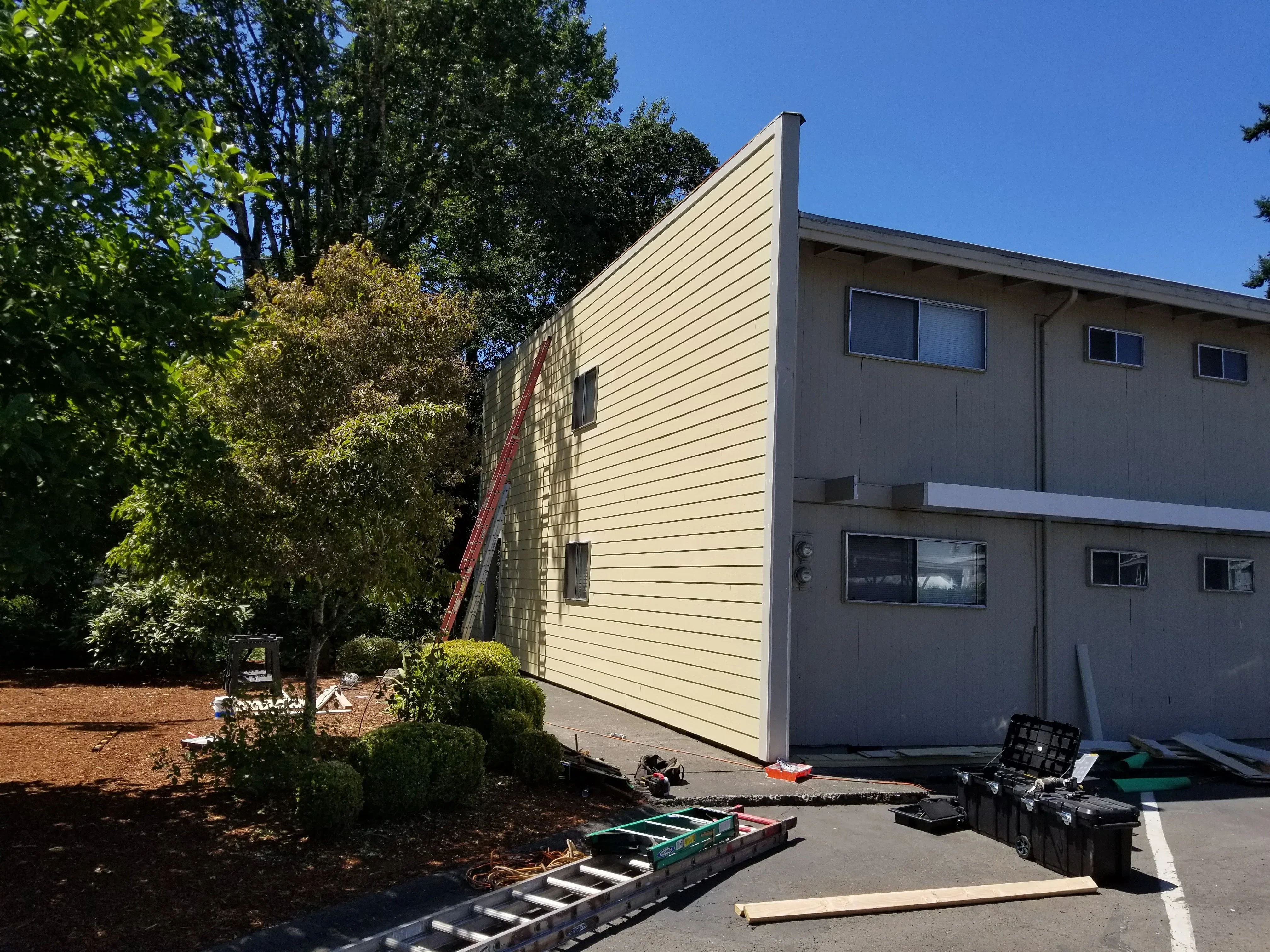 Cream-colored horizontal vinyl siding with new windows installed on multi-story residential home