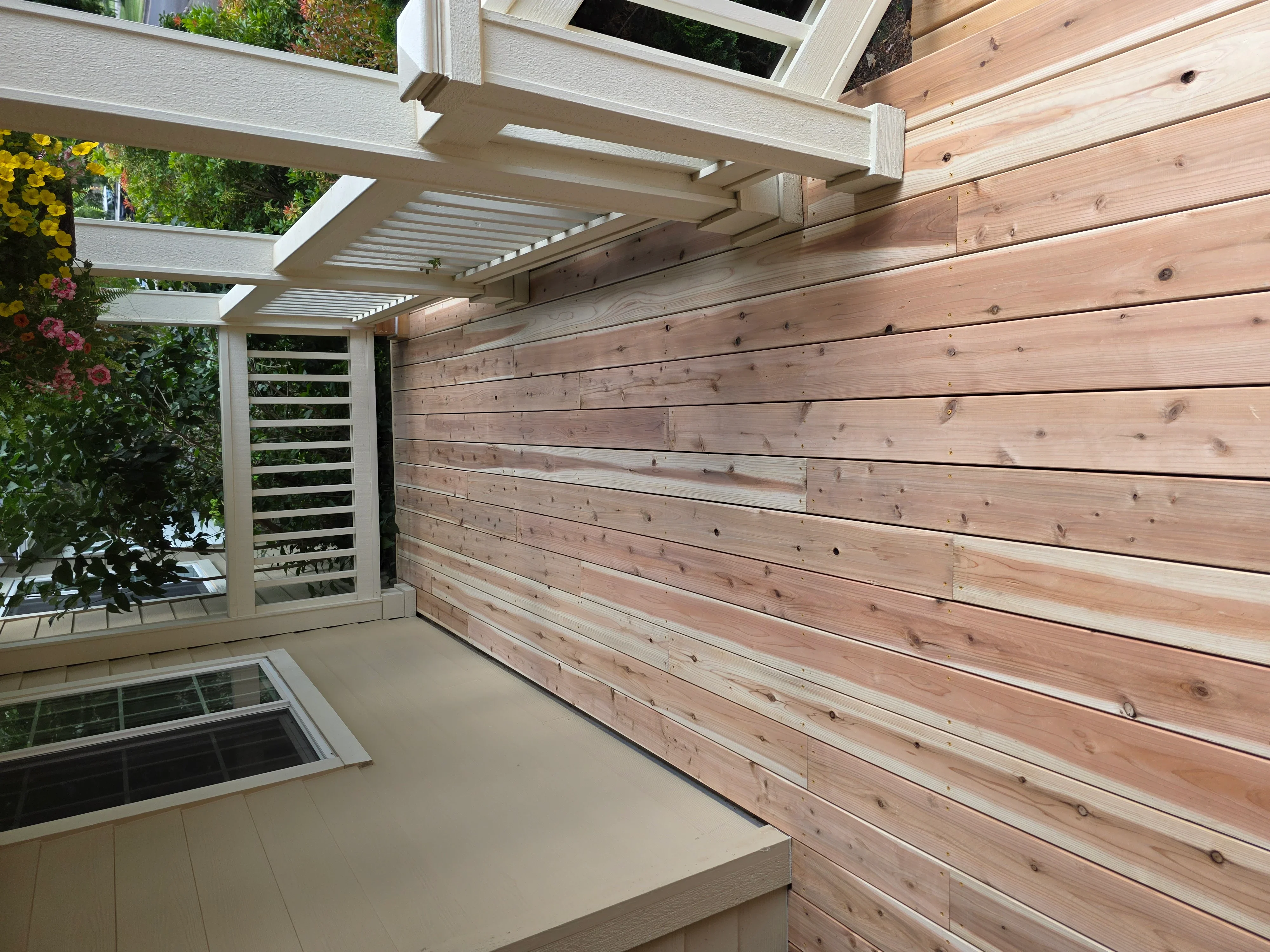 White aluminum pergola with adjustable louvers and cedar horizontal siding walls