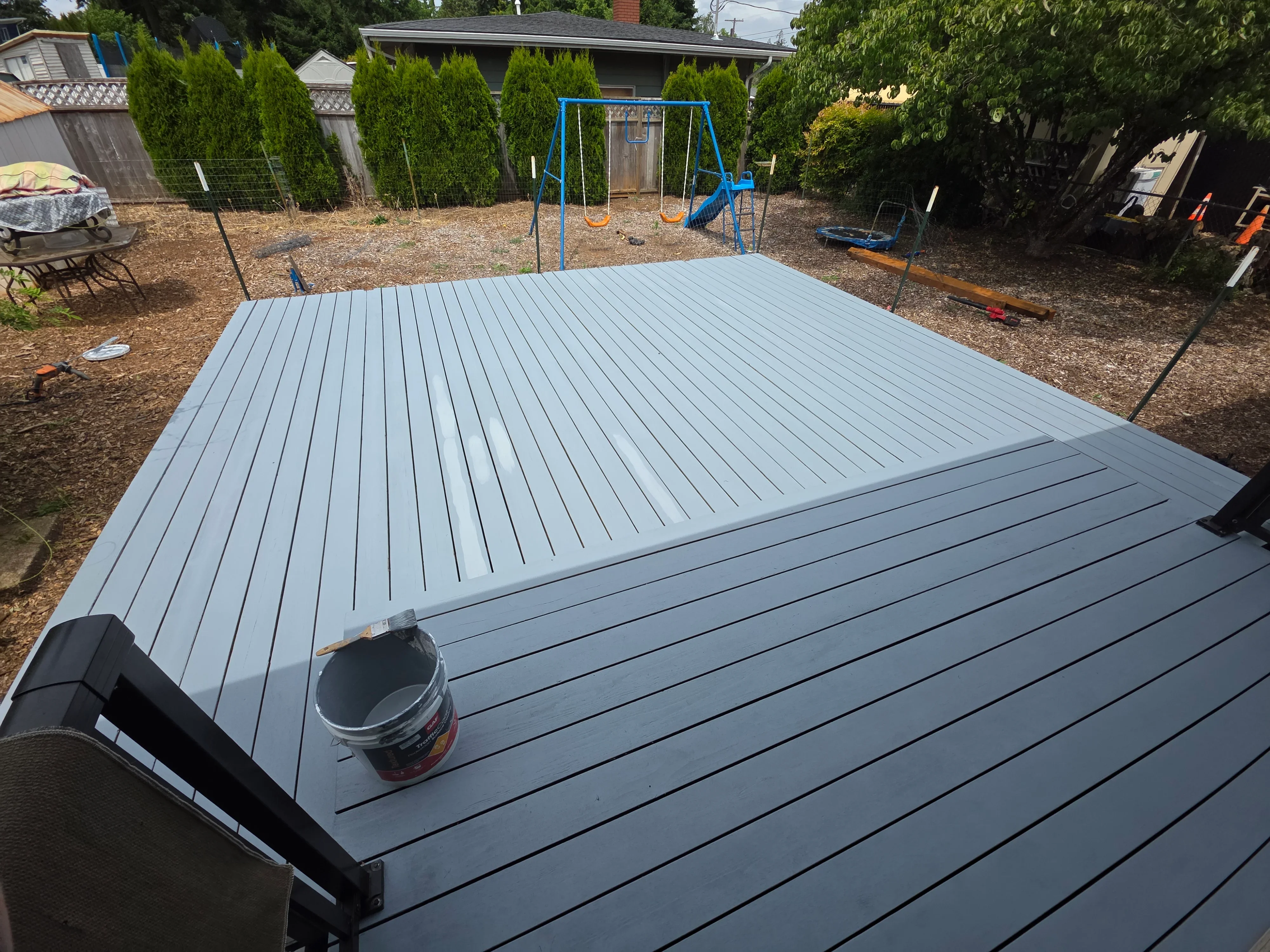 Gray composite deck with linear board pattern in residential backyard setting